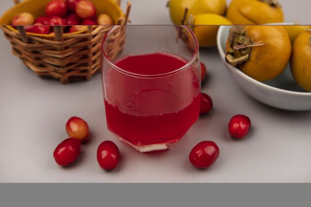 新鲜在灰色墙壁上的桶上放着一杯新鲜的山茱萸果汁和山茱萸水果的顶视图玻璃杯顶部视野
