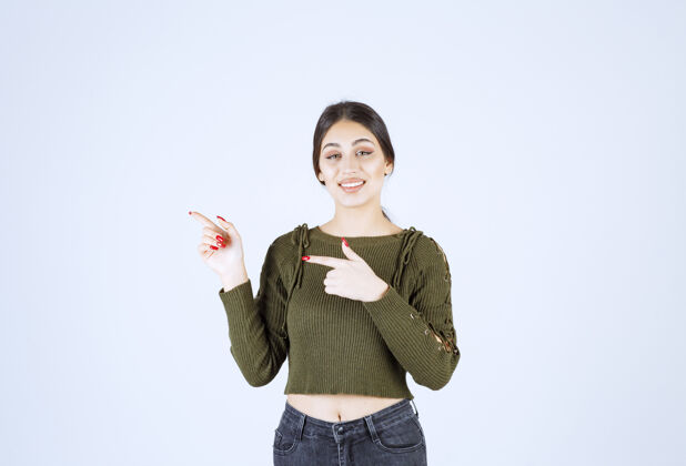 女士一个年轻的女模特站在一边用食指指着照片女人女孩肖像