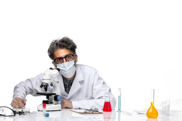 医学前视图中年科学家穿着特殊的白色西装使用显微镜使用化学视图