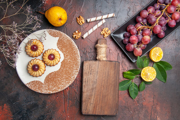 柑橘顶视图美味的小饼干与葡萄在黑暗的地板蛋糕甜饼干糖健康成熟深色
