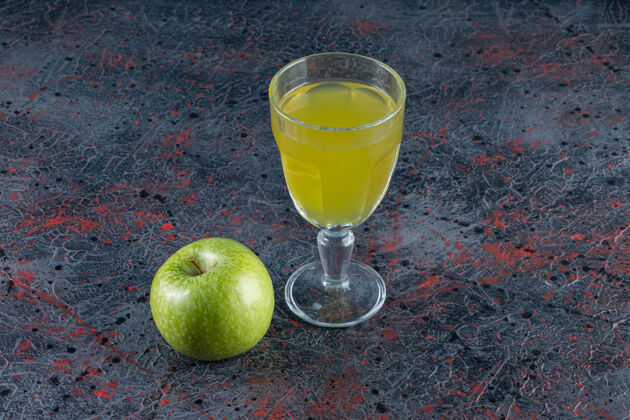 有机一个完整的绿色苹果水果和一杯果汁放在石桌上生的食物颜色