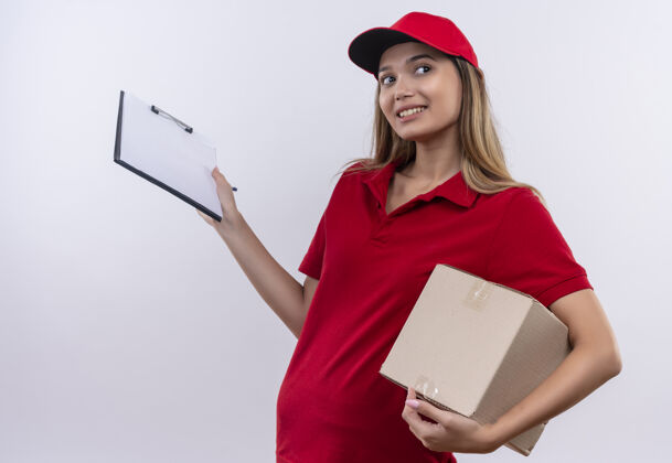帽子看着身边喜气洋洋的送外卖的小女孩 穿着红色制服 戴着帽子 拿着盒子和剪贴板隔离在白色的墙上请穿壁板剪贴板