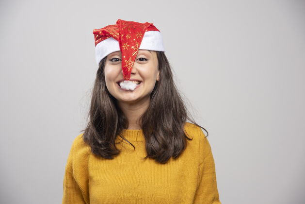 礼品盒年轻的女人想吃掉圣诞老人的红帽子圣诞节女模型