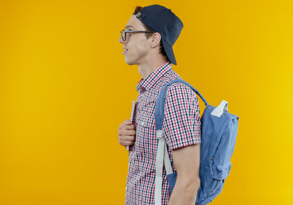 白色站在侧视图年轻的学生男孩戴着背袋和眼镜和帽子的白色年轻立场学生