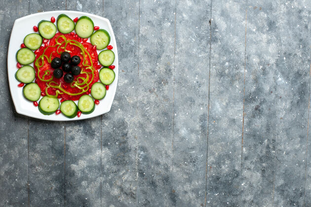 顶部顶视图切片黄瓜和橄榄在一个灰色的桌子沙拉蔬菜色维生素健康饮食盘子里沙拉蔬菜桌子