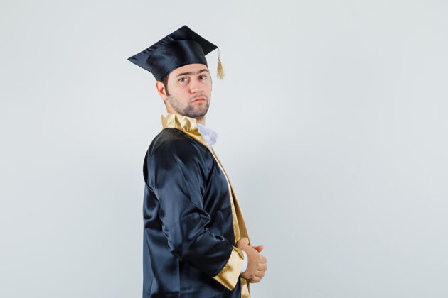 男人身穿研究生制服的年轻男子拿着他的礼服 看上去很自信男人毕业模特