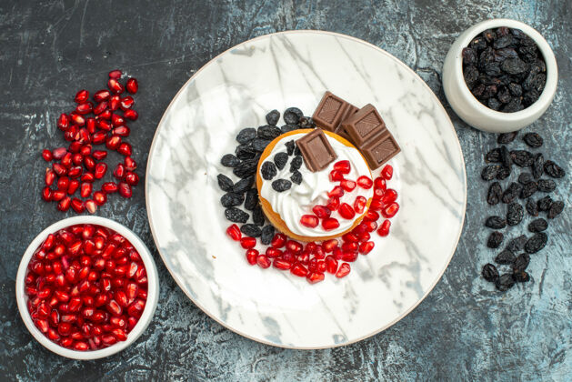 美味的奶油蛋糕顶视图美味的奶油蛋糕与巧克力石榴和葡萄干浅黑色的背景葡萄干派陶器