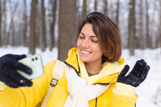 自然年轻美丽快乐开朗的女子在冬季森林视频博客 自拍照片科技肖像电话