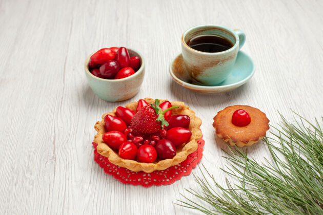草莓前视小蛋糕上有水果和一杯茶 白色桌面上有水果甜点彩茶杯子水果盘子