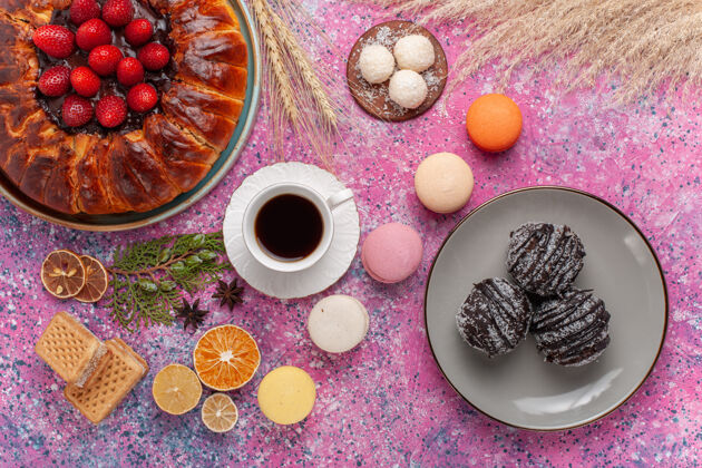 茶俯瞰美味的草莓派与法国马卡龙和蛋糕粉红色圆美味糖果