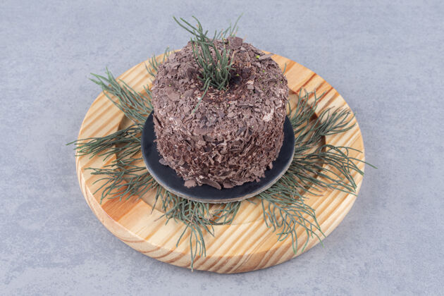 叶子松叶和蛋糕放在大理石桌上的木盘上蛋糕美味烘焙食品