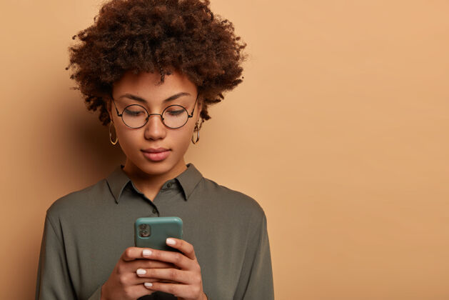 人特写严肃的美国黑人妇女在智能手机上输入信息应用现代技术