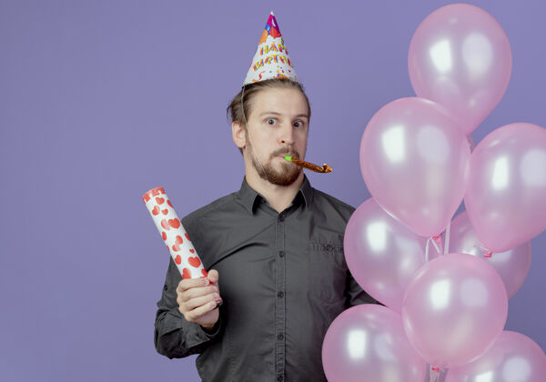 氦一个戴着生日帽的帅哥拿着氦气球和五彩纸屑大炮在紫色的墙上吹哨子生日男人哨子