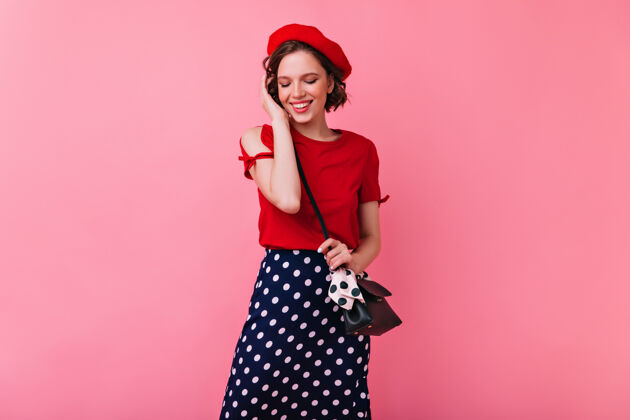 肖像一个穿着红色上衣的白人女人微笑着俯视着一张害羞的法国女孩戴着贝雷帽的室内照片时尚室内乐趣