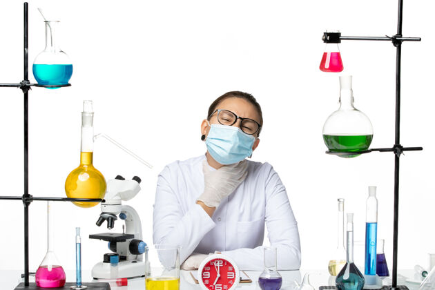 实验室前视图穿着医疗服的女化学家带着面罩坐在白色背景上的溶液化学病毒实验室病毒-飞溅诊所药品医疗