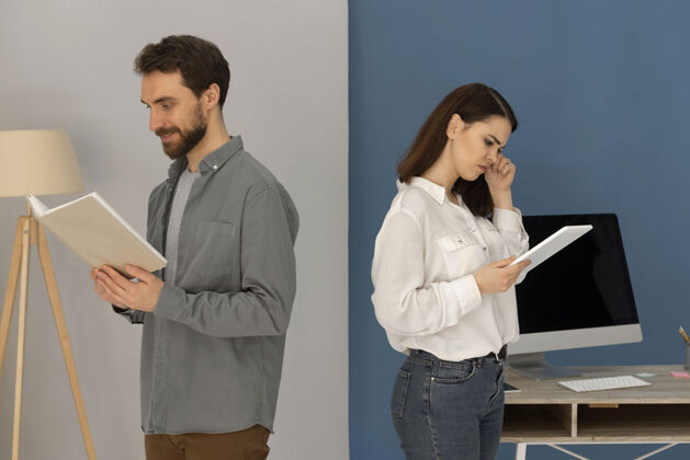 女性背靠背的男人拿着书 女人拿着平板电脑放松讲座男人