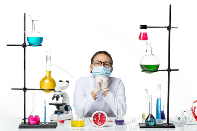 喷溅前视图穿着医疗服的女化学家 戴着面罩 坐在白色背景上的解决方案病毒实验室化学冠状病毒飞溅坐姿设备实验室