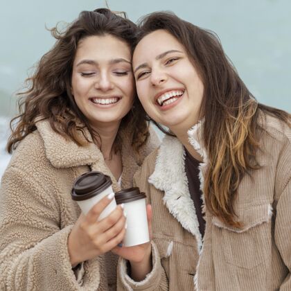 女人带咖啡杯的中镜头快乐女人户外中景生活方式