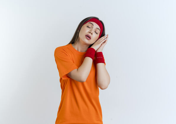佩戴疲惫的年轻运动女性戴着头带和腕带做着闭眼睡觉的姿势腕带年轻成人