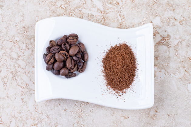 拼盘把咖啡豆和磨碎的咖啡粉放在一个漂亮的盘子里美味粉末研磨