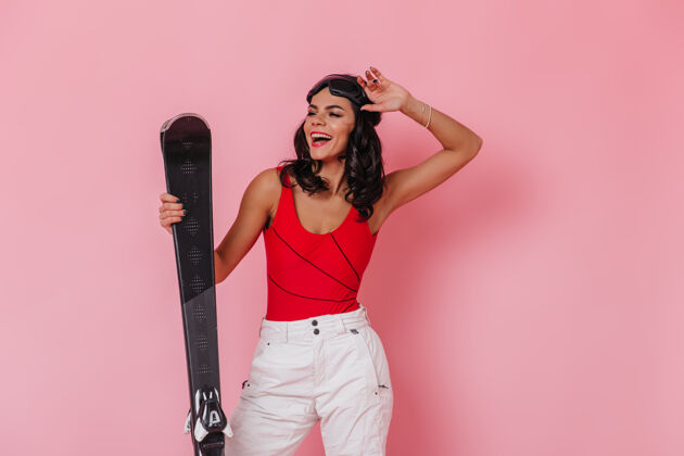 快乐一个穿着白裤子拿着滑雪板的女人年轻微笑运动