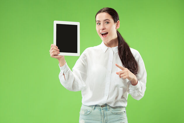 笔记本电脑一个自信的休闲女孩的肖像 显示绿色背景下笔记本电脑的空白屏幕欢呼微笑年轻