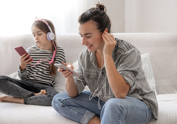 女儿欢快的母女俩正在家里休息 戴着耳机听音乐音乐放松孩子