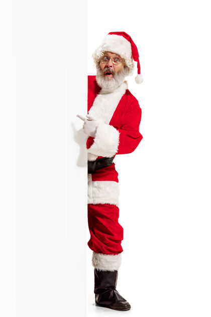 服装快乐惊喜的圣诞老人指着空白的广告横幅背景和复制空间微笑的老人在白色空白的空白海报显示微笑节日礼物