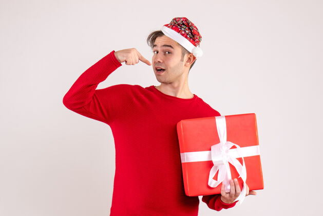 礼物正面图：戴着圣诞帽的年轻人拿着白色背景的礼物圣诞老人年轻人风景