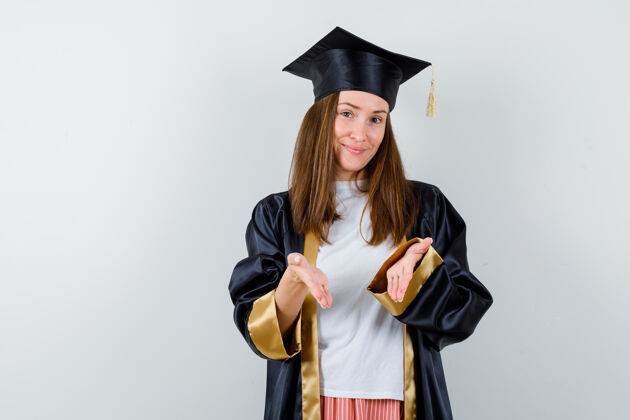 成人毕业的女人穿着休闲服做欢迎手势 穿着制服 看上去很开朗前视图学士长袍成功