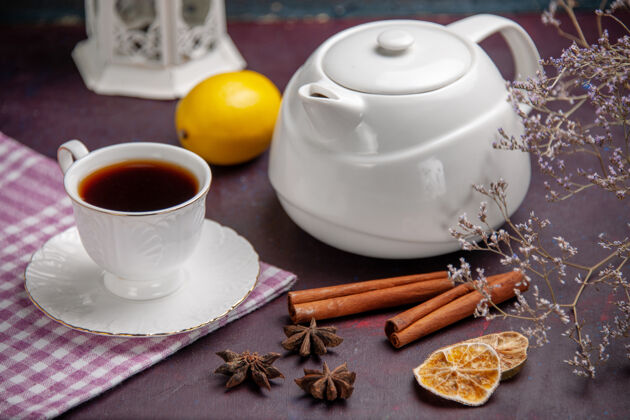 餐正面近看一杯茶 用桂皮和茶壶在深色的茶面上喝柠檬色的茶碟肉桂水壶
