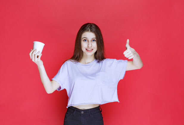 成人年轻女子手持白色一次性水杯 露出满意的表情喜欢人产品