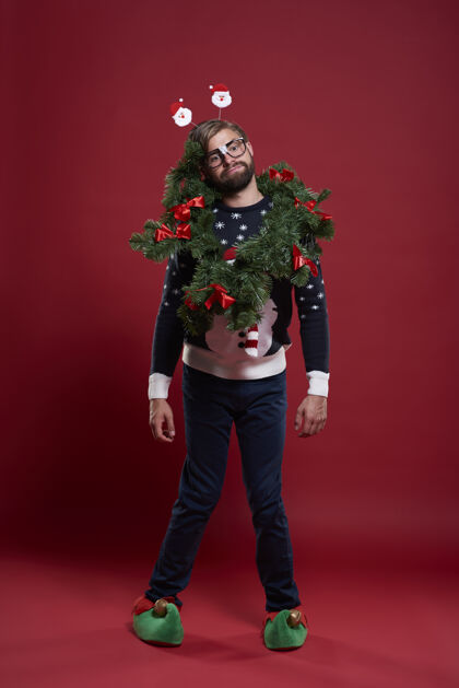思考穿着圣诞服装和花环的男人开衫包装眼镜