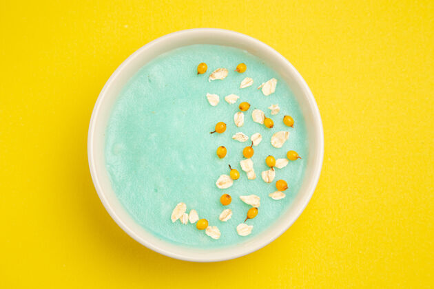 容器顶视图蓝色的冰甜点在黄色的桌子上的盘子里牛奶谷类食品的颜色水谷类食品食物