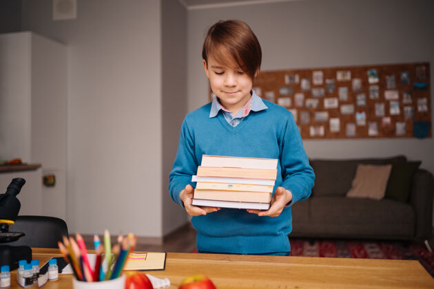 教育一年级男生在家学习 手里拿着一堆书 准备上网上课学习学生在线