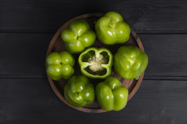 生的整个和切片的青椒放在木制深色桌子上高品质的照片农业健康辣椒粉