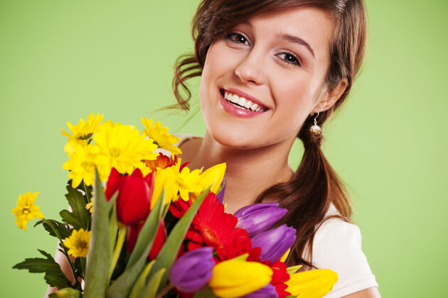 多种颜色带着鲜花的快乐年轻女子花束肖像可爱