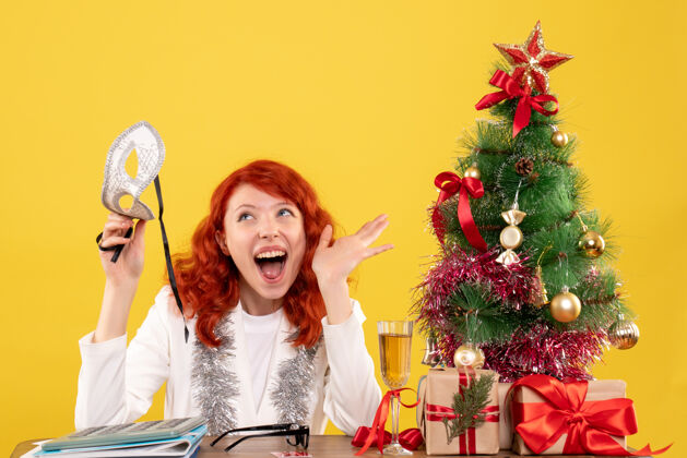 颜色前视图女医生拿着面具围着圣诞树和礼物年份情感树