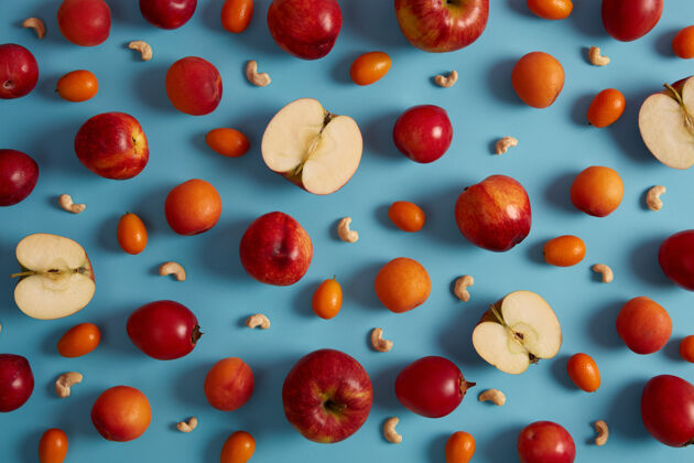 异国情调上图为红色成熟的苹果 桃子 番茄 金橘和营养丰富的腰果 背景为蓝色美味水果的创意组合维亚明甜食 健康营养理念切片开销美味