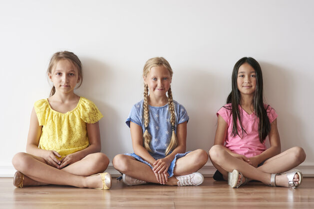 学生三个女孩盘腿坐着快乐微笑学生
