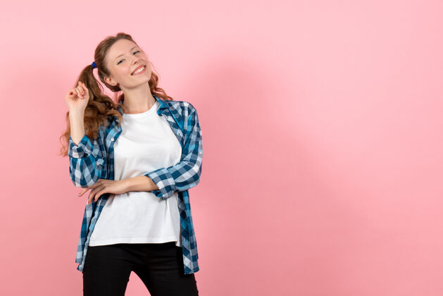 漂亮正面图：穿着蓝色格子衬衫的年轻女性在粉色背景上摆姿势 女性儿童青春色彩情感模型姿势肖像成人