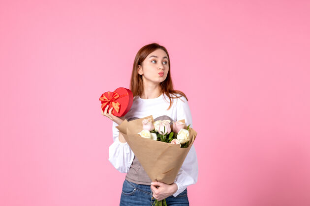 礼物正面图：带花的年轻女性 在粉色背景上作为妇女节礼物呈现玫瑰色水平三月女性约会女性感官平等人礼物玫瑰