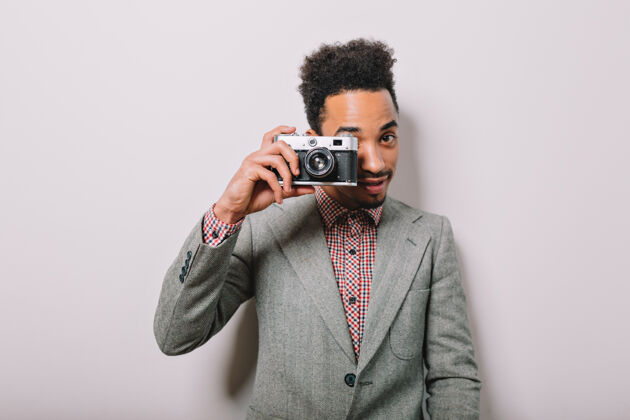 欢呼现代时尚的美国黑人男子在白色的墙上摆姿势 用复古相机拍摄灰色非洲站立男性