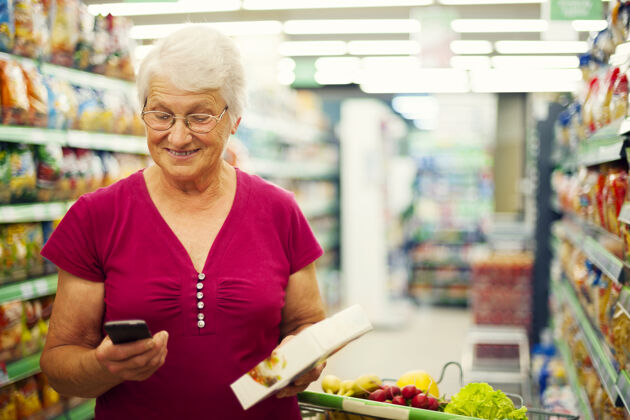市场资深女士在超市发手机短信杂货店蔬菜简介
