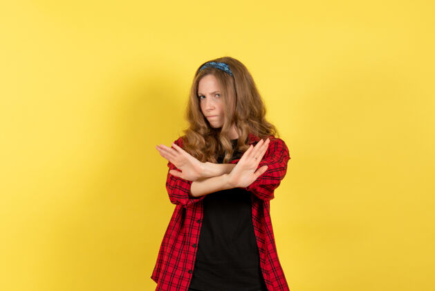 姿势正面图穿着红色格子衬衫的年轻女性在黄色背景上摆姿势模特儿女颜色情感人类成人前面年轻女性