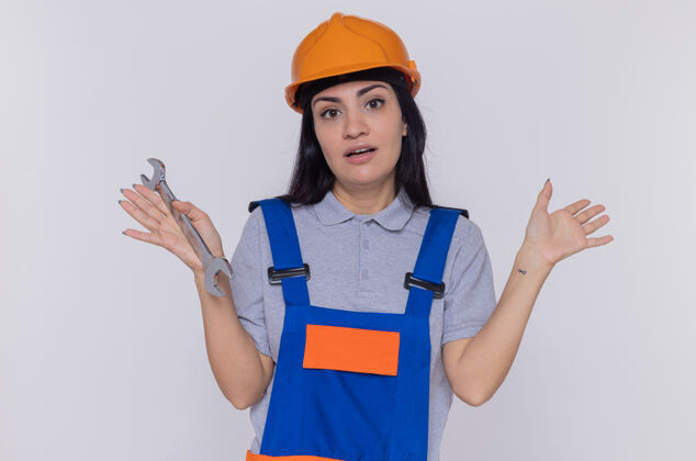 年轻穿着施工制服和安全帽的年轻建筑工人女人安全站立