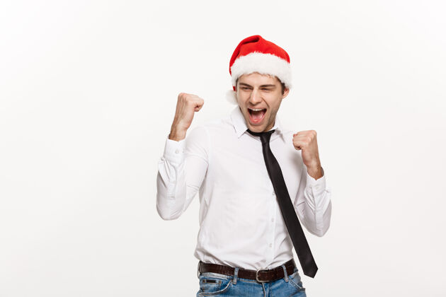 男性帅气的商人戴着圣诞老人的帽子 在白色的脸上摆出令人惊讶的表情面部红色圣诞节
