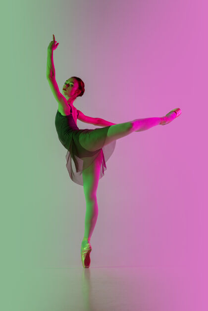 游戏轻年轻而优雅的芭蕾舞演员在霓虹灯下被隔离在渐变的粉绿色墙壁上艺术 动作 动作 灵活性 灵感概念灵活的芭蕾舞演员 失重跳跃舞蹈渐变能量