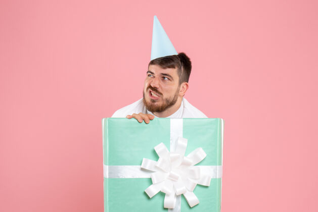 爱国正面图：年轻男性站在礼物盒内 参加粉色圣诞照片彩色情感睡衣派对情感帽子睡衣