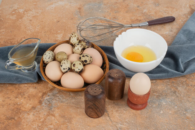 食物白鸡蛋和鹌鹑蛋放在篮子里 蛋黄放在白盘子里油胡椒木头